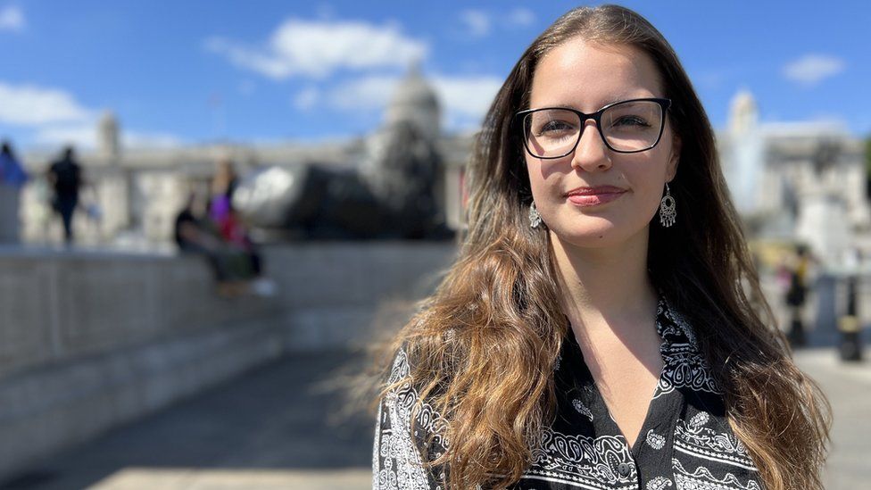 Rebecca, 21, smiles at the camera in London's Trafalgar Square