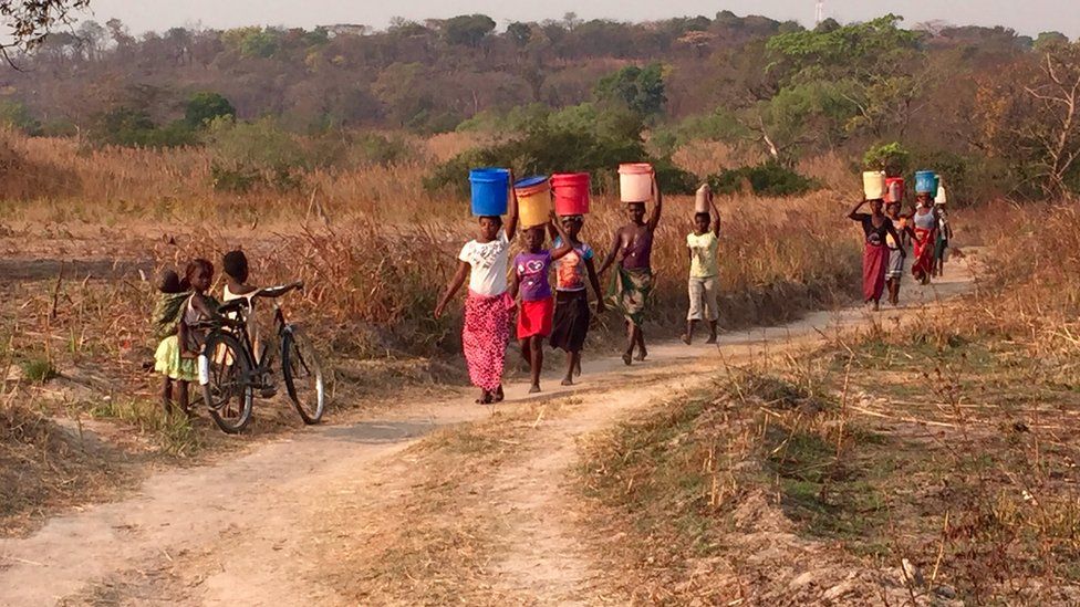 The women of Hippo Pool village carry water collected from the Kafue River in Zambia's copper belt