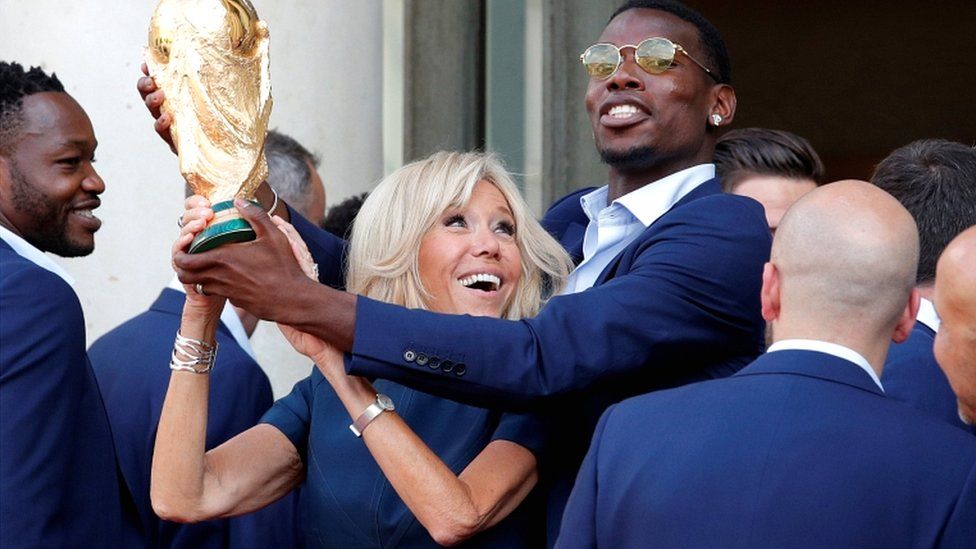 Brigitte Macron and player Paul Pogba hold the World Cup trophy at the Elysée palace in Paris on 16 July 2018