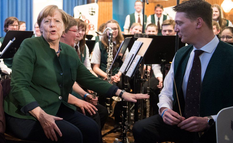 German Chancellor Angela Merkel speaks with musicians of a band at an election rally in Brilon
