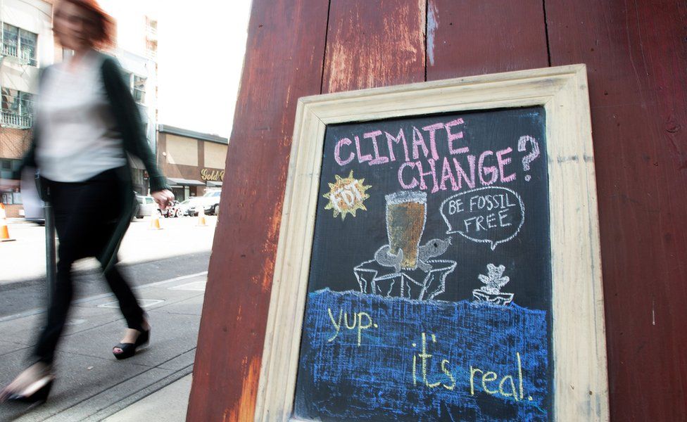 A woman walks by a sign about climate change in front of a bar in downtown San Francisco. September 2018