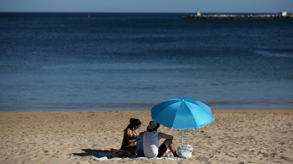 People enjoy the sun at the beach in Cascais, Portugal