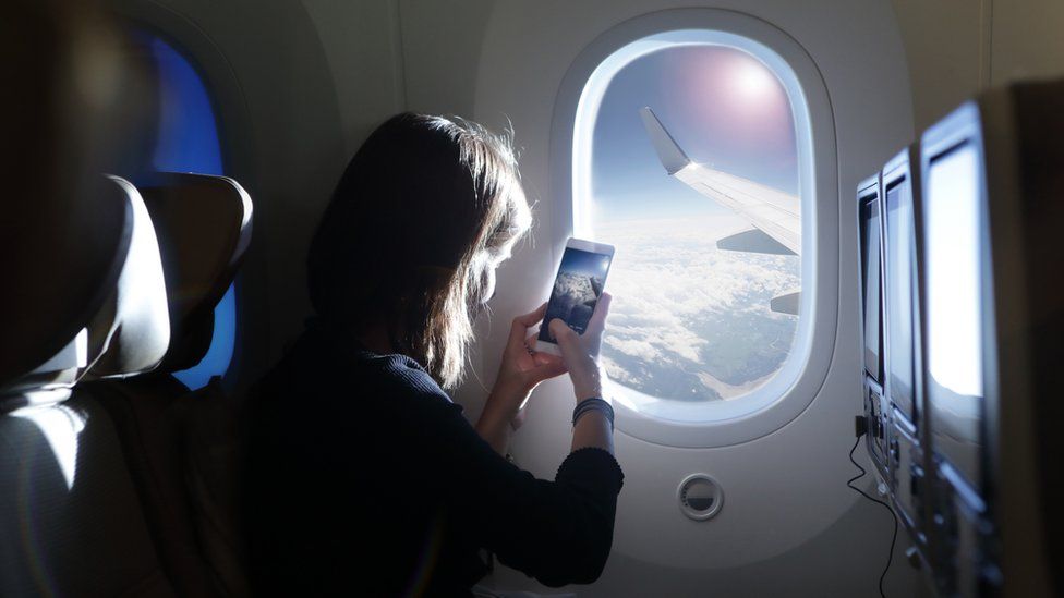 A woman takes a picture out of a plane window