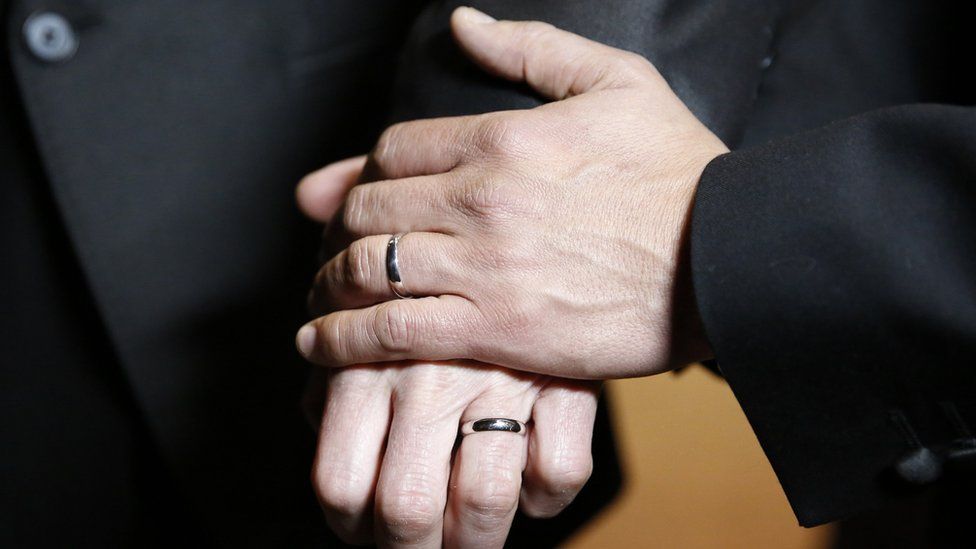 Two men hold hands with wedding rings on after one of the first gay weddings in England in 2014