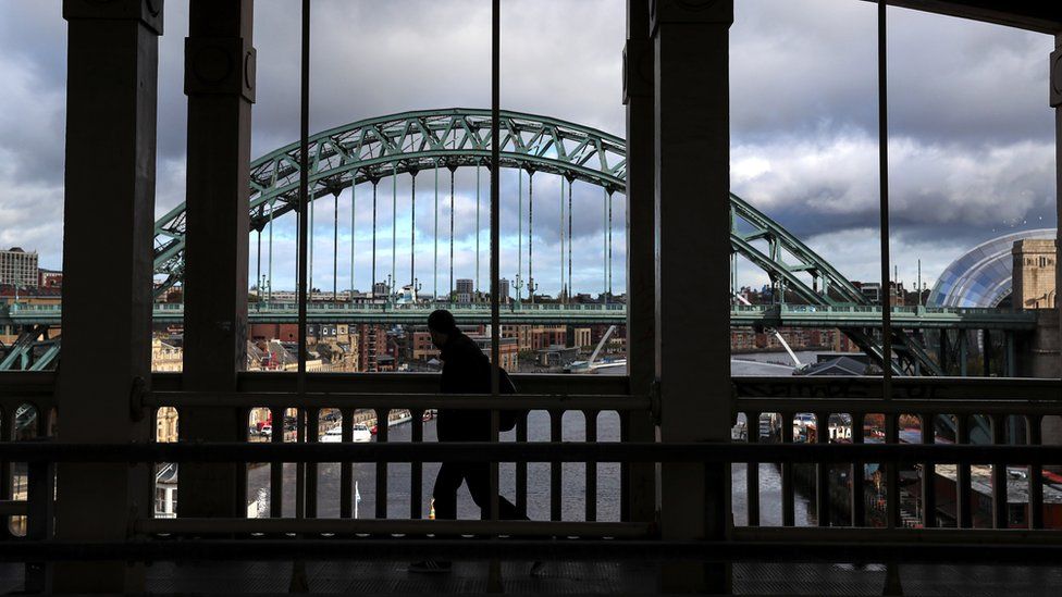 A pedestrian crosses the High Level Bridge between Gateshead and Newcastle, with the Tyne Bridge in the background