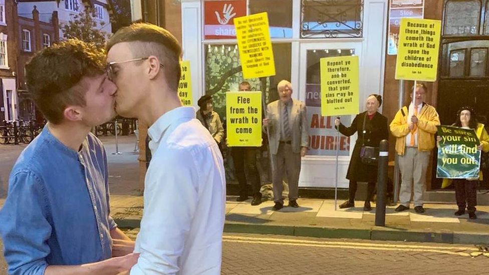 Joe Fergus and Robert Brookes kissing in front of protesters