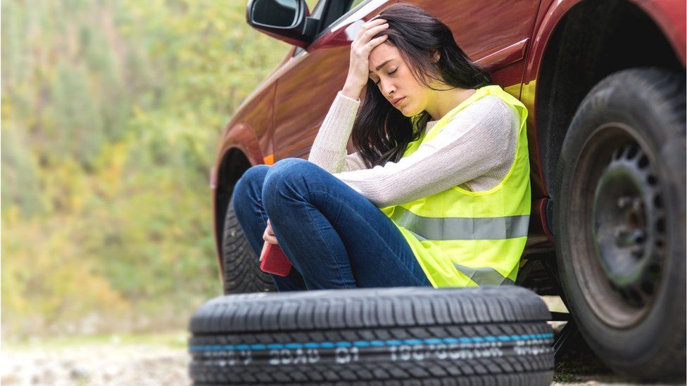 Fed-up woman with car tyre