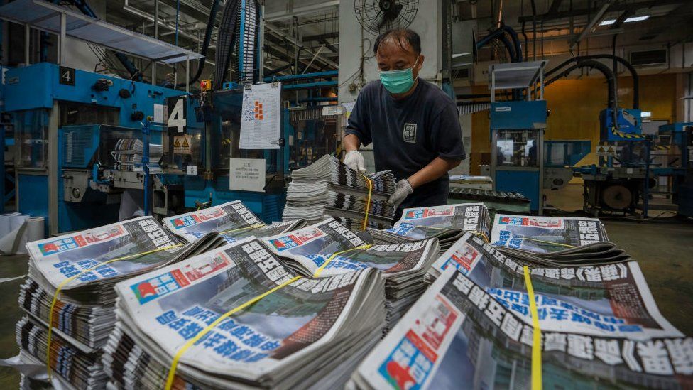 An employee stacks freshly printed papers onto a pallet in the printing facility of the Apple Daily newspaper offices in Hong Kong