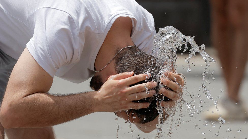 A man cools off in a fountain during hot weather in Cordoba