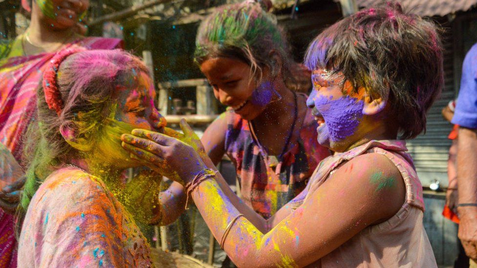 Two girls are seen smearing each other with colored powder during Holi celebration in Kolkata , India , on 5 March 2023 .