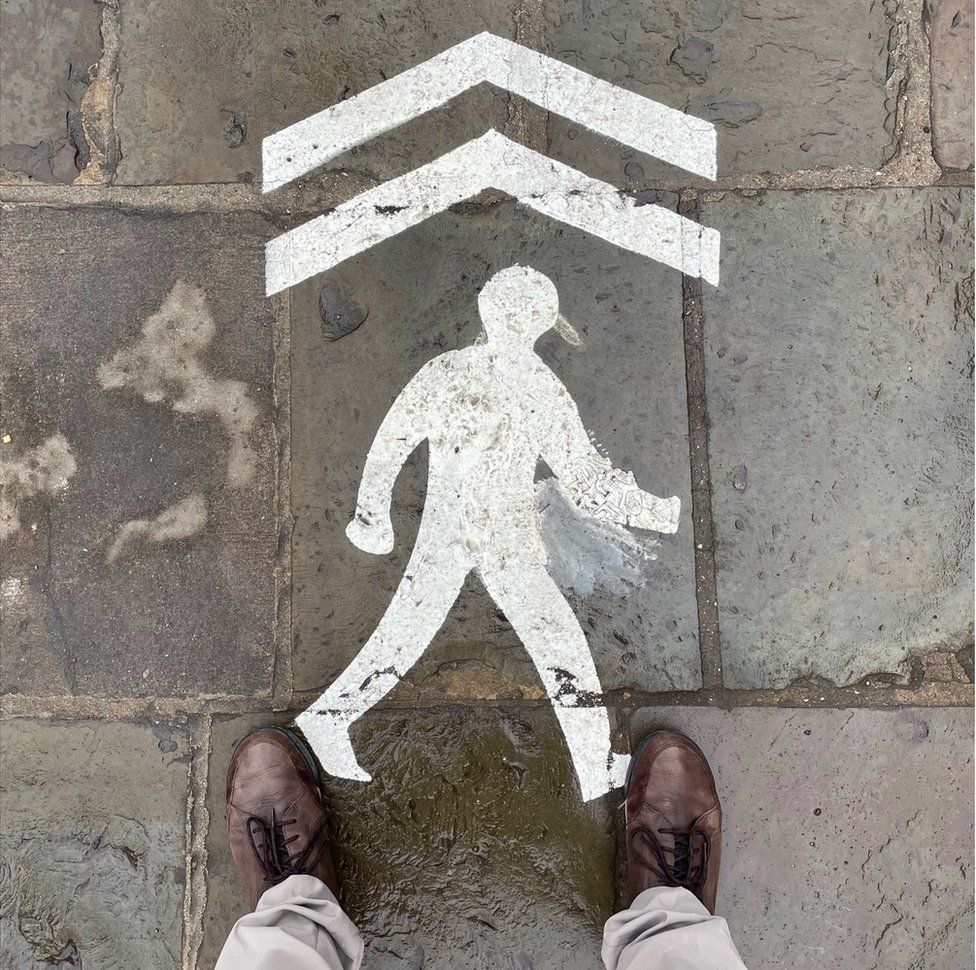 A stencil outline of a walking figure with an arrow