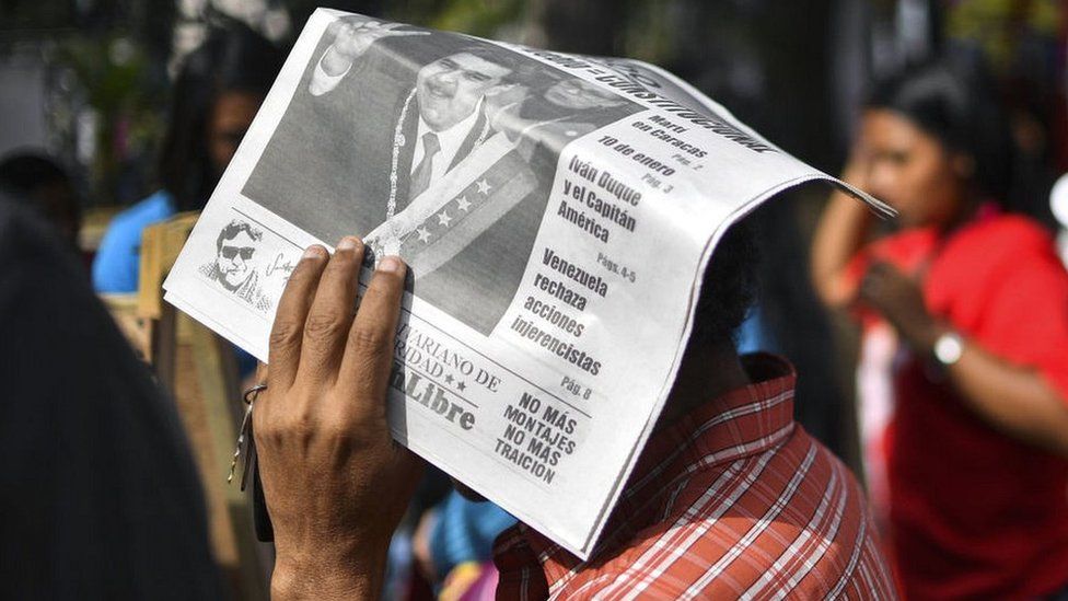 A man protects himself from the sun with a newspaper featuring Venezuelan President Nicolas Maduro, February 2019