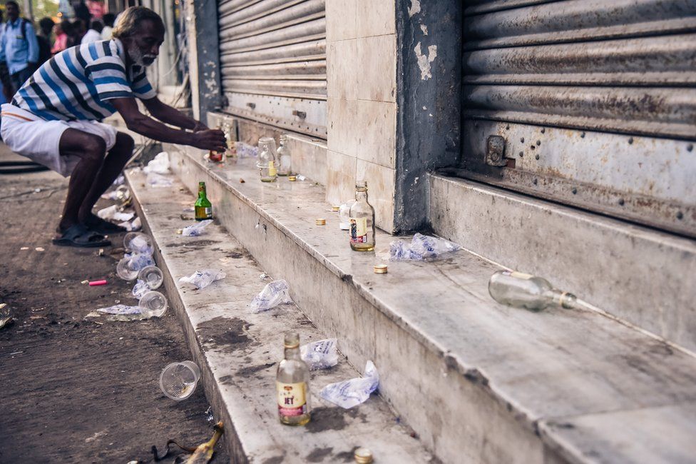 Empty bottles and cups are strewn about near alcohol shops