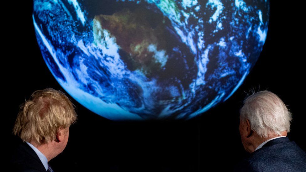 Boris Johnson and David Attenborough looking at planet earth graphic