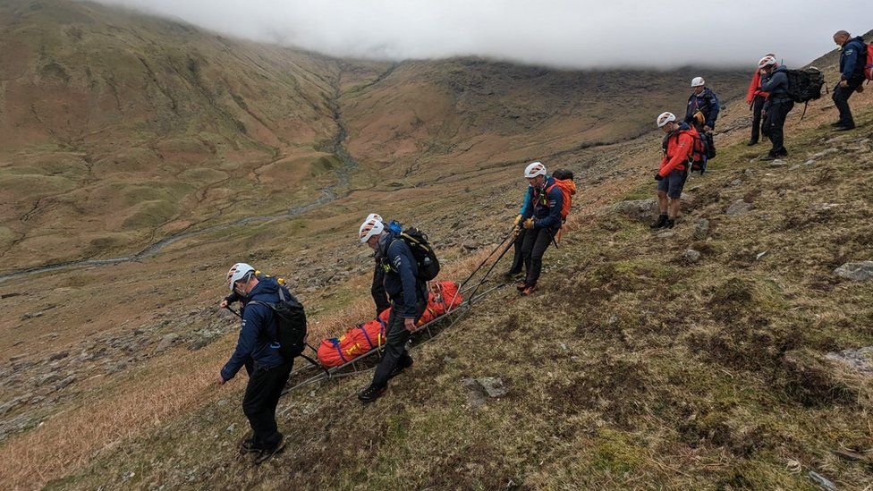 Rescuers carry the casualty down the fell on a stretcher