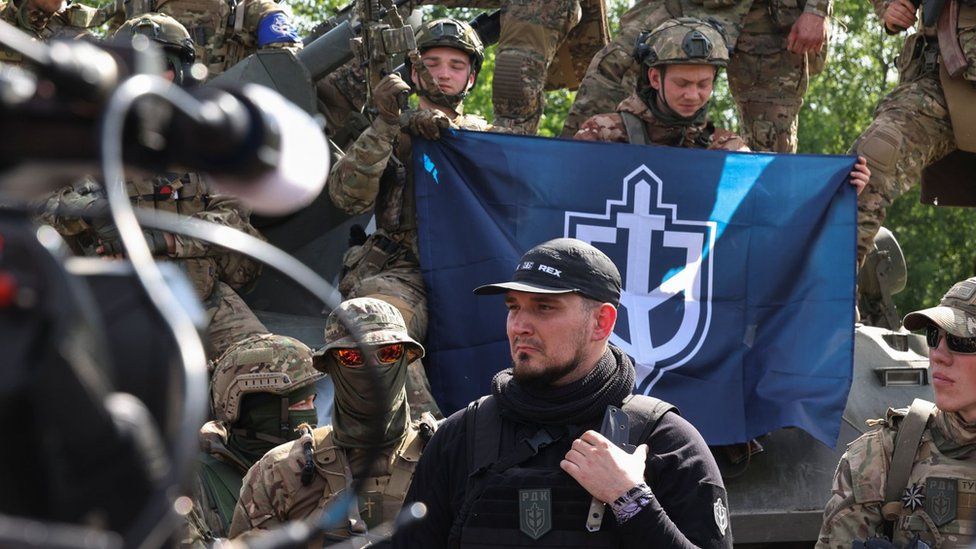 Denis Kapustin (centre) flanked by Russian Volunteer Corps fighters talk to reporters in Ukraine. Photo: 24 May 2023