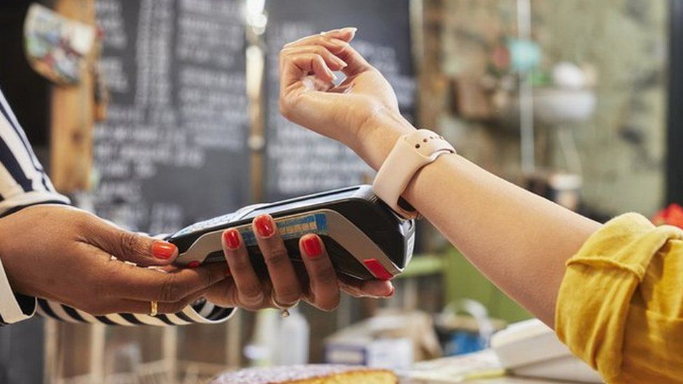 Person paying at cafe counter using smart watch