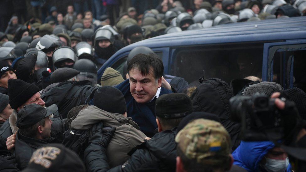 Georgian former President Mikheil Saakashvili struggles out of a police car in Kiev
