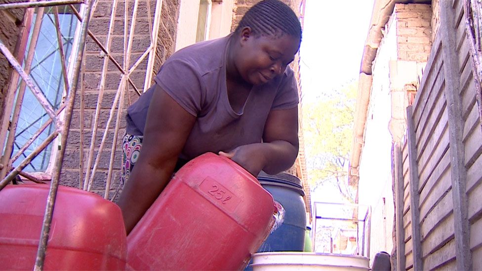 A woman pouring water from a gallon.