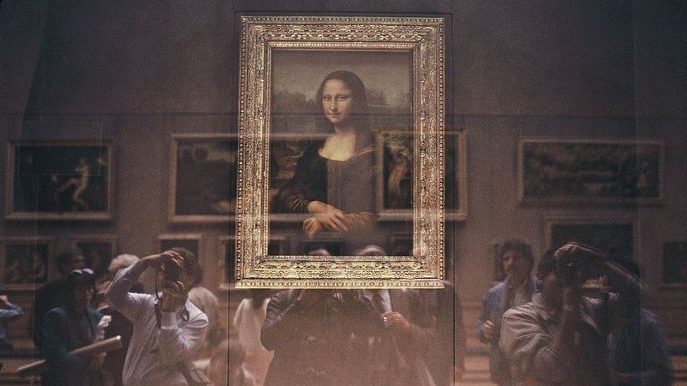 The Mona Lisa behind its bullet-proof glass protection with Japanese tourists at the Louvre Museum