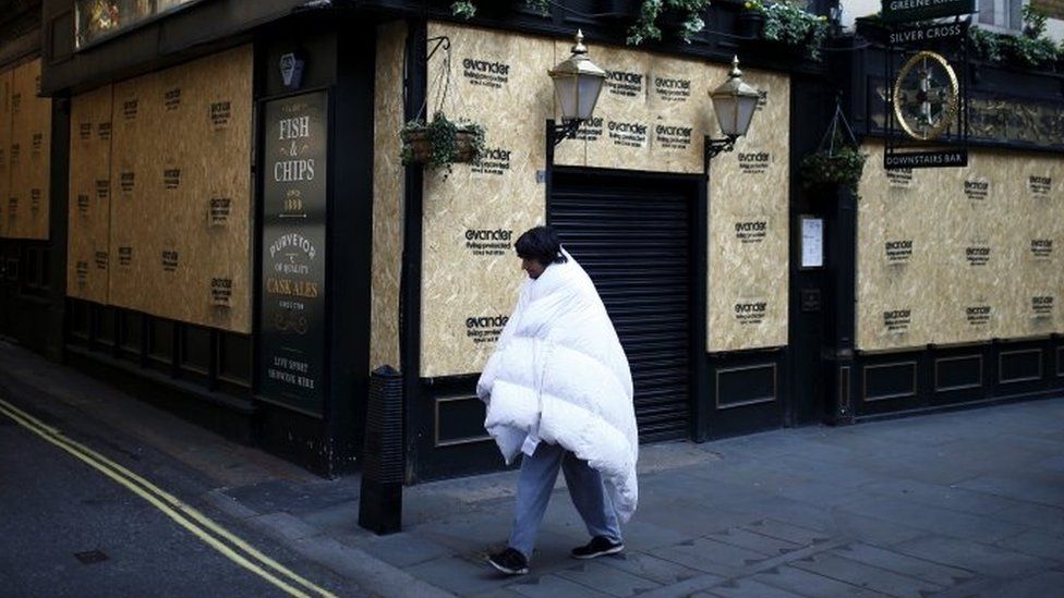 A homeless man walks past the Silver Cross pub in Whitehall - April 2020