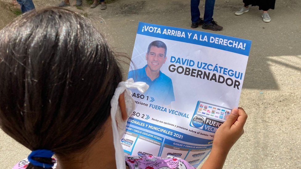 A woman holds a David Uzcátegui campaign poster