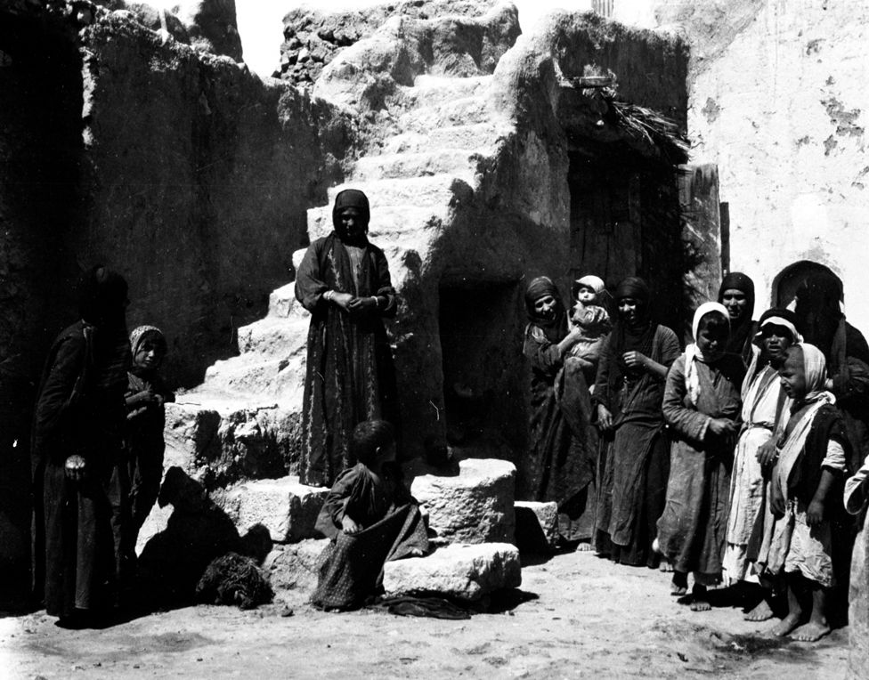Photograph from Gertrude Bell Archive: People standing outside a house in a courtyard in Palmyra
