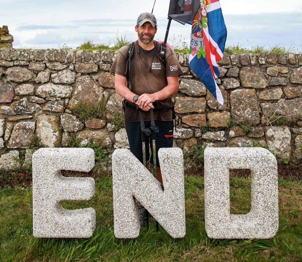 Mark Harding stands next to a big sing syaing end