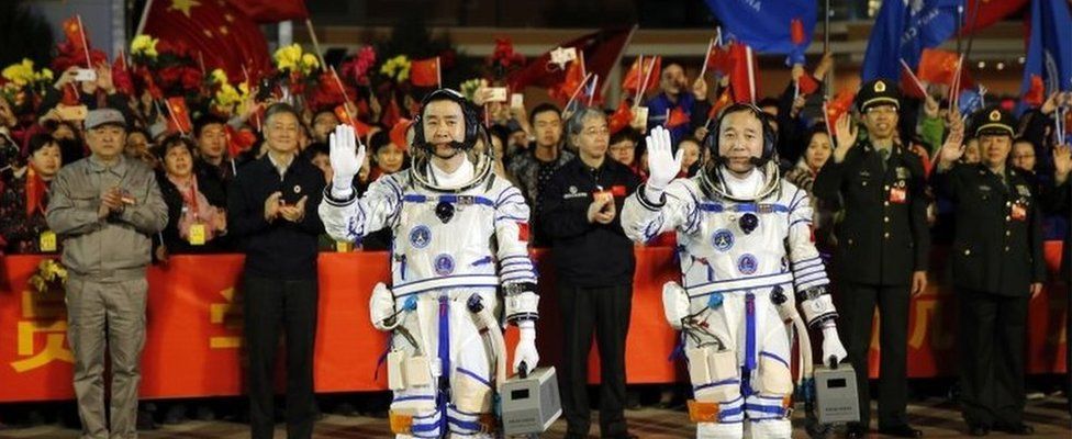 Chinese astronauts Jing Haipeng, right, and Chen Dong, left, wave farewell to the crowd before getting on Shenzhou 11 spacecraft at the Jiuquan Satellite Launch Center in northwest China on 17 October