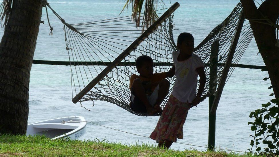 Two children in a hammock by the sea in Fiji