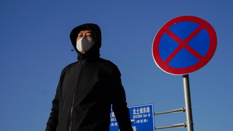 A man wearing a face mask walks on the street in Beijing, China, 05 December 2022.