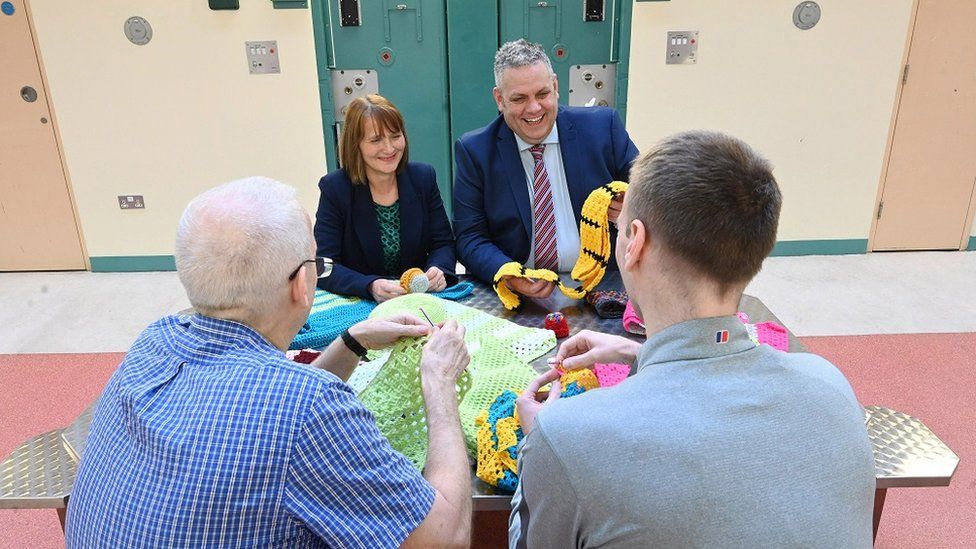 Governor of Maghaberry Prison, David Savage and Julie McConville, Assistant Director for Specialist Child Health and Disability with the Southern Health & Social Care Trust, review the crocheting work of the ‘Stitch in Time Gang’