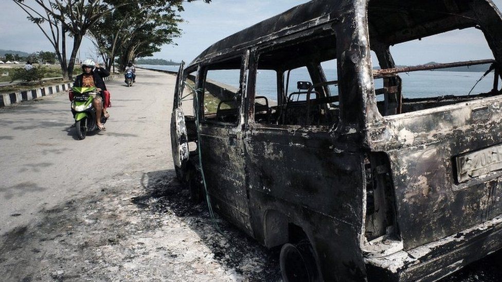 A burnt out car on the West Papuan coastline