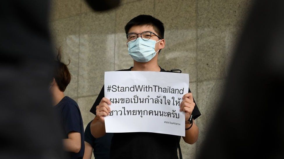 Pro-democracy activist Joshua Wong (C) holds a placard in solidarity with ongoing pro-democracy protests in Thailand