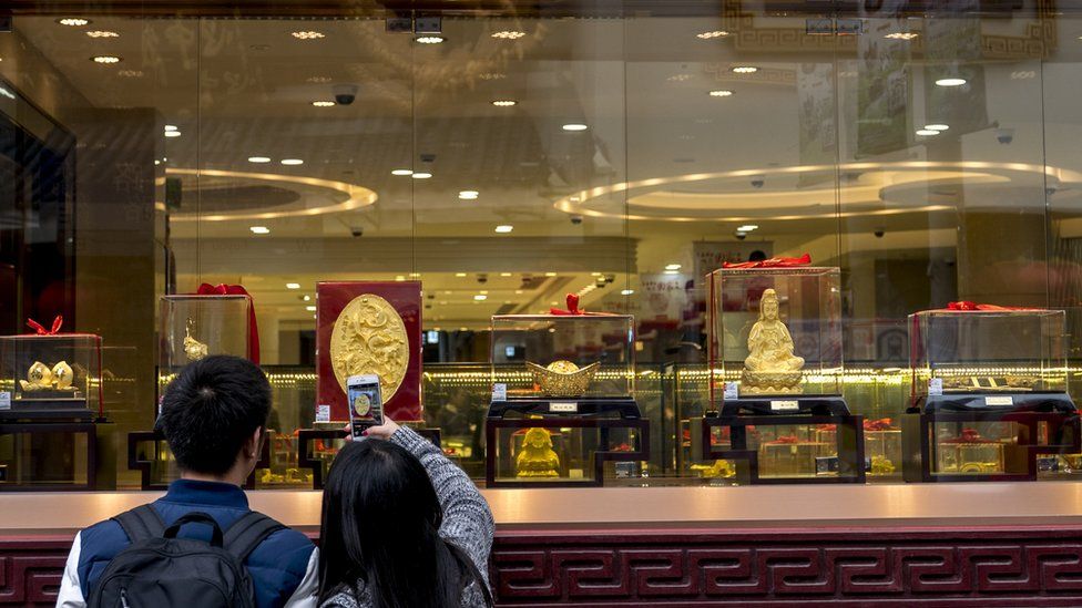 Consumers take pictures of gold commodities in a gold shop window, 2015. " An overbuilt property market and a devaluation of the yuan have already made Chinese investors the worlds largest consumers of gold"