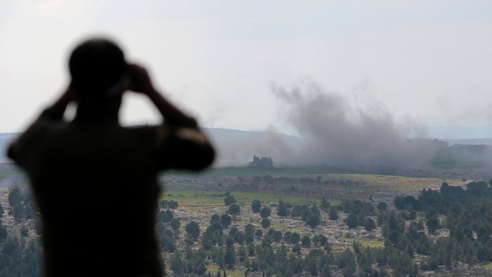A Turkey-backed Free Syrian Army soldier watches with binoculars as smoke rises after a bomb attack during an offensive, at Der Mismis Village, southeast of Afrin, Syria.