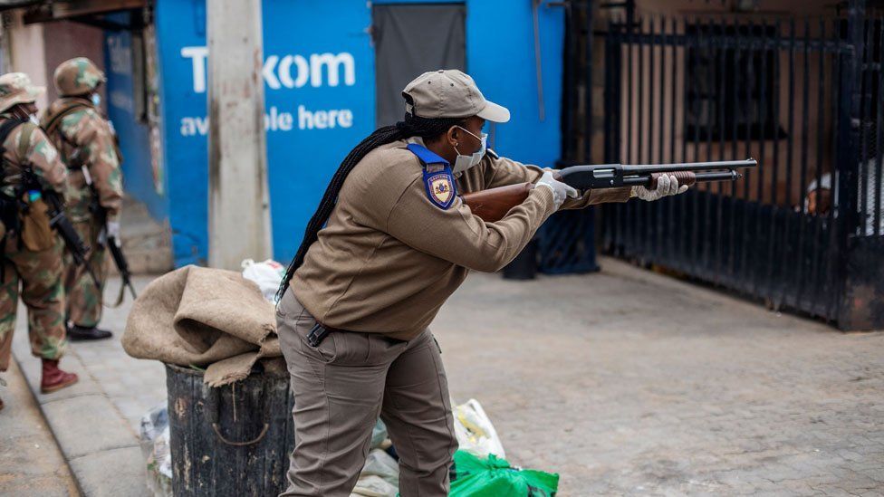 A Gauteng Traffic Police officer shoots rubber bullets to urge residents to go inside during a mixed patrol of South African National Defence Force (SANDF) and Gauteng Traffic Police in Alexandra, Johannesburg