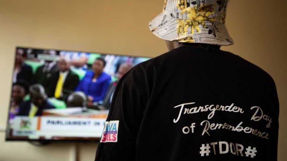 A Ugandan transgender woman who was recently attacked and currently being sheltered watches a TV screen showing the live broadcast of the session from the Parliament for the anti-gay bill, at a local charity supporting the LGBTQ Community near Kampala on March 21, 2023.