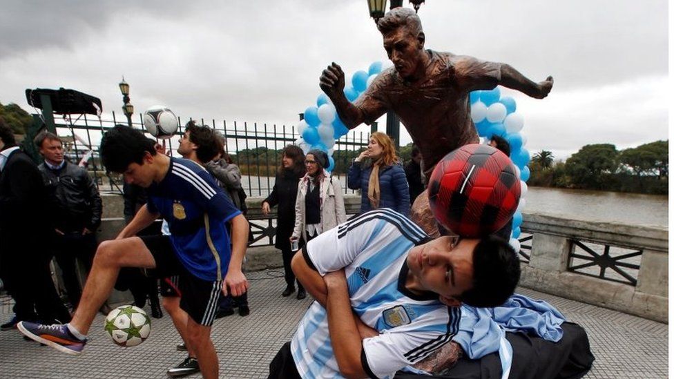 Boys play with soccer balls in front of the statue of Argentina's player Lionel Messi after it was unveiled in Buenos Aires, Argentina, June 28, 2016