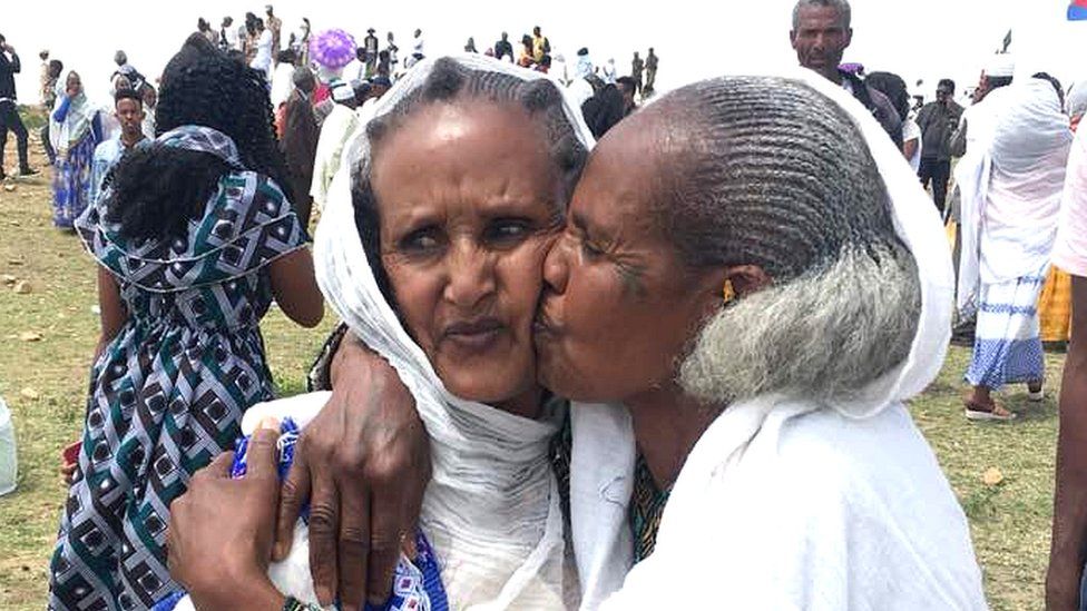 One woman kissing another on the cheek