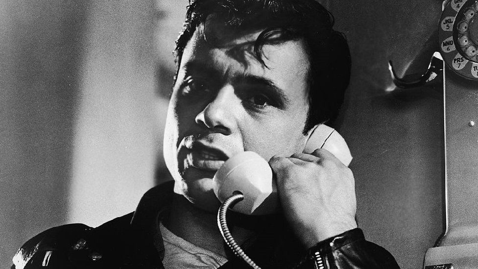 American actor Robert Blake talks on a pay telephone in a still from the film, 'In Cold Blood,' directed by Richard Brooks, 1967.