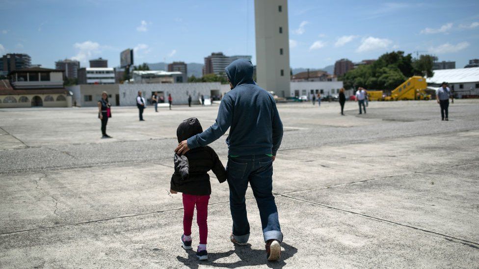 Un padre camina junto a su hija en el aeropuerto de Brownsville, TX, rumbo a un vuelo de deportacion.