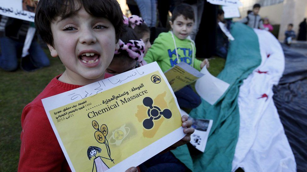 A child holds up a poster saying Syrians would never forget the August 2013 chemical weapons attack in Damascus, outside the UN headquarters in Beirut (26 December 2015)