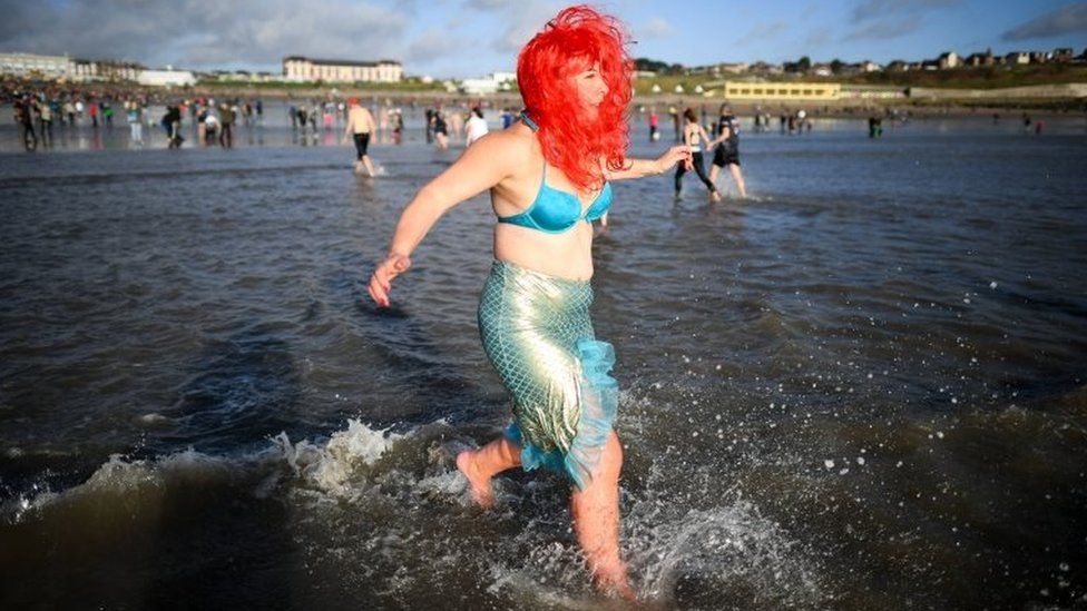 A swimmer runs into the sea at the Barry Island New Year Day Swim at Whitmore Bay, in the Vale of Glamorgan, South Wales, d