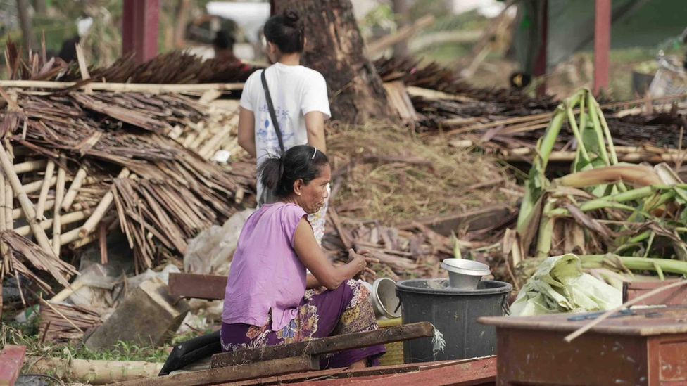 Residents in Sittwe sit among the fallen trees and destroyed homes and debris