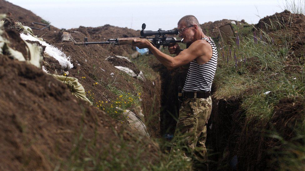 A Ukrainian volunteer fighter searches for pro-Russian separatists in the village of Shyrokyne, Donetsk region on 3 July 2015