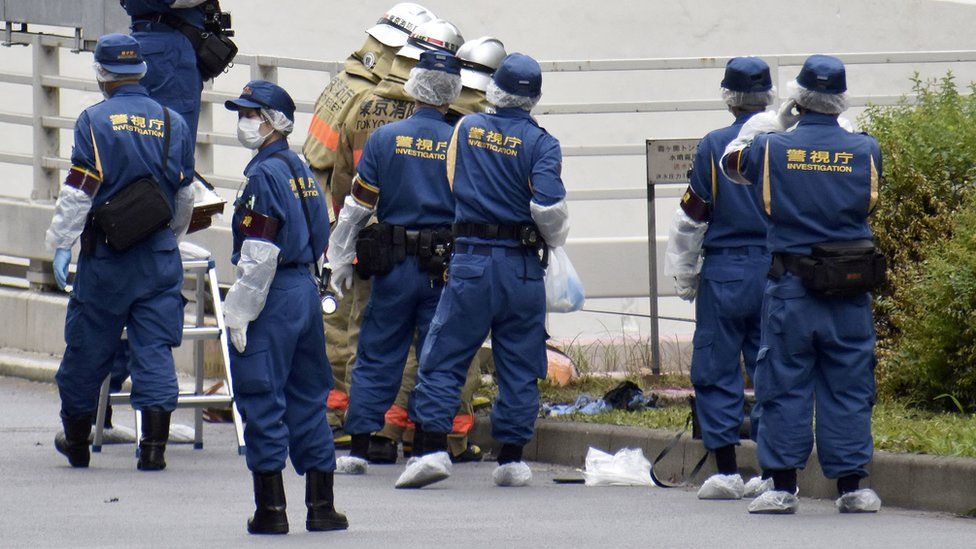 Police and firefighters inspect the scene in Tokyo where a man set himself on fire