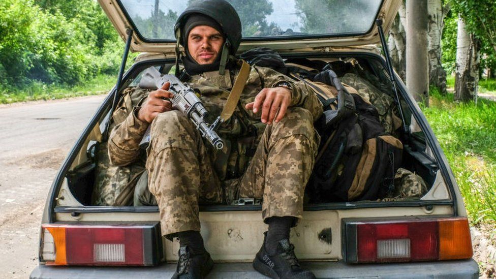 A Ukrainian soldier sits in the boot of a car