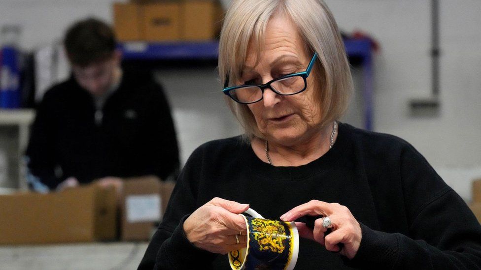 A worker sticks the paint on official chinaware in a pottery in Stoke-on-Trent