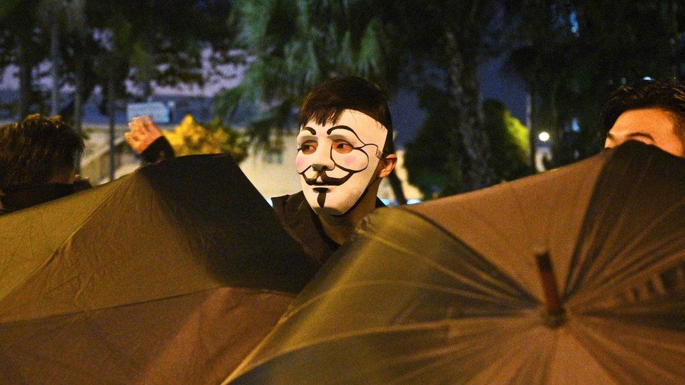 A protester looks out from behind some umbrellas in Hong Kong